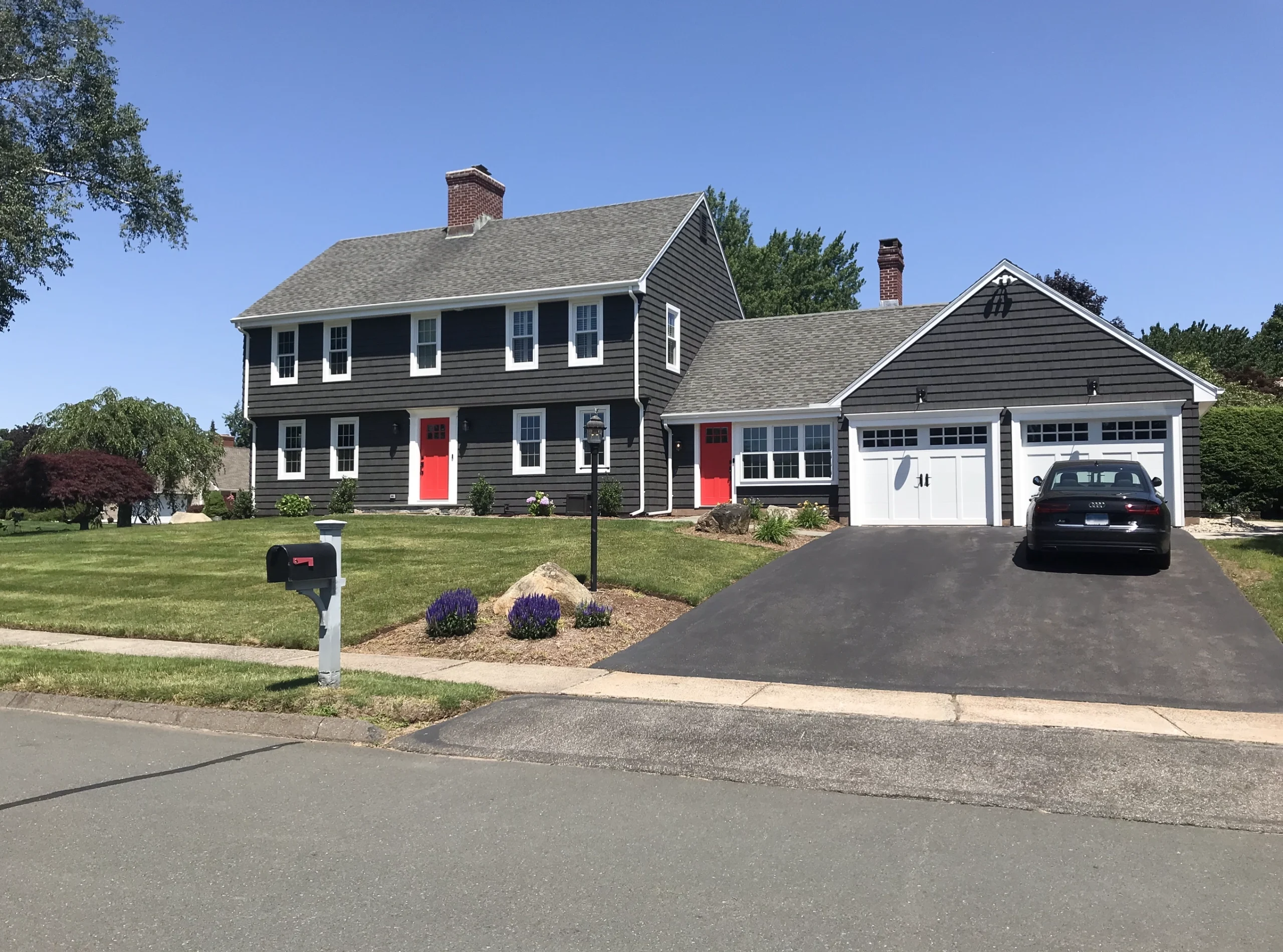 Modern and minimalistic house remodeling with Dark Gray Vinyl Siding and a Red Door