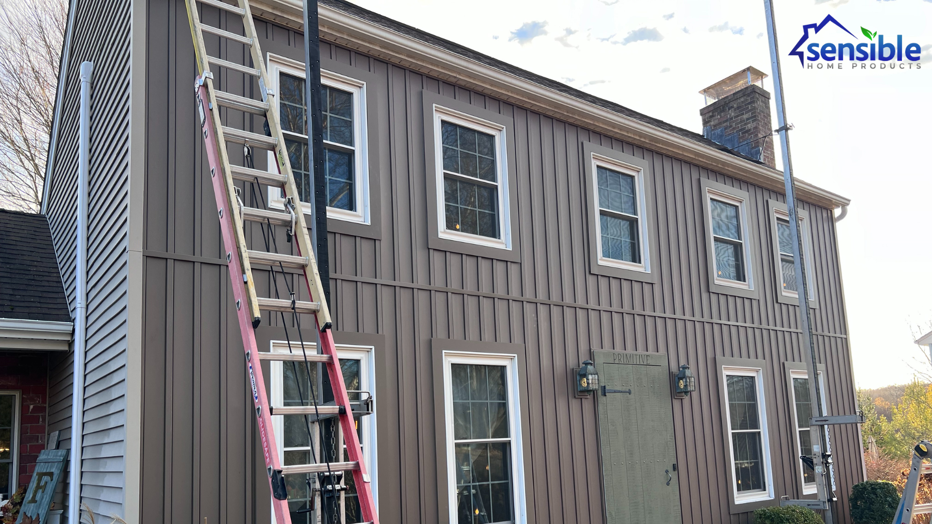 House exterior during gutter replacement installation, featuring scaffolding and ladders set up for precise work on the updated rain gutter project.